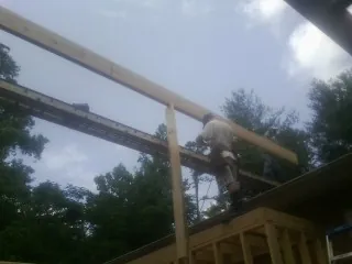 Carpenter setting a ridge beam over a new addition frame — Ice Dam Removal by Roofing Brothers in Maumee