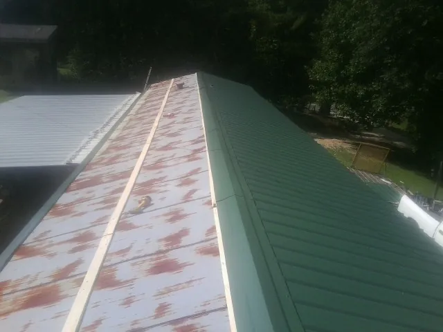Old rusted panels beside newly installed green metal roofing — Wind Damage Roof Repair by Roofing Brothers in Maumee