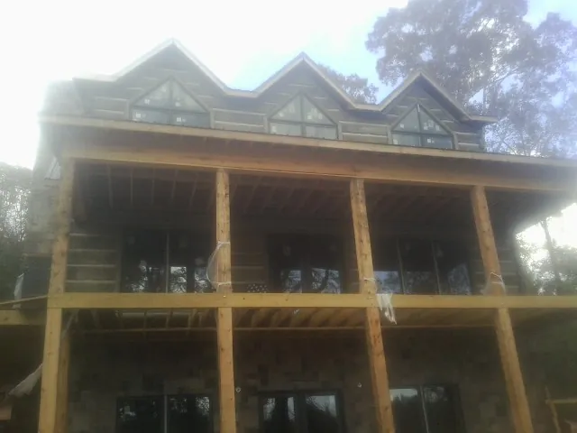 Dormers and porch framing on a large log home under construction — Roof Coating work by our crew in Maumee