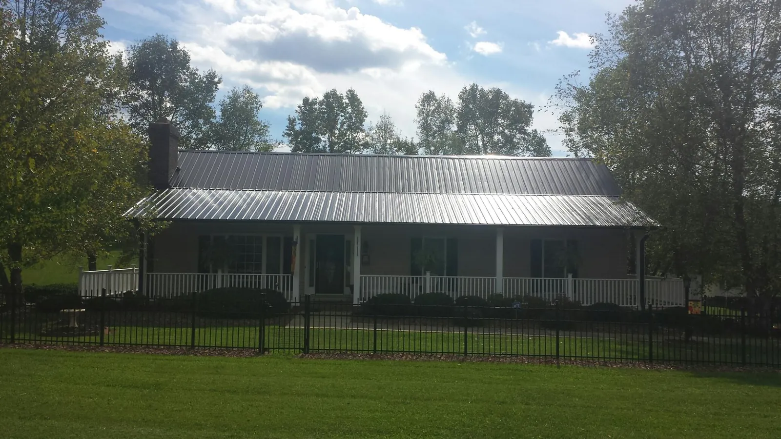 Gray metal roof on a brick ranch with a full width front porch — Gutter Guard Installation work by our crew in Maumee