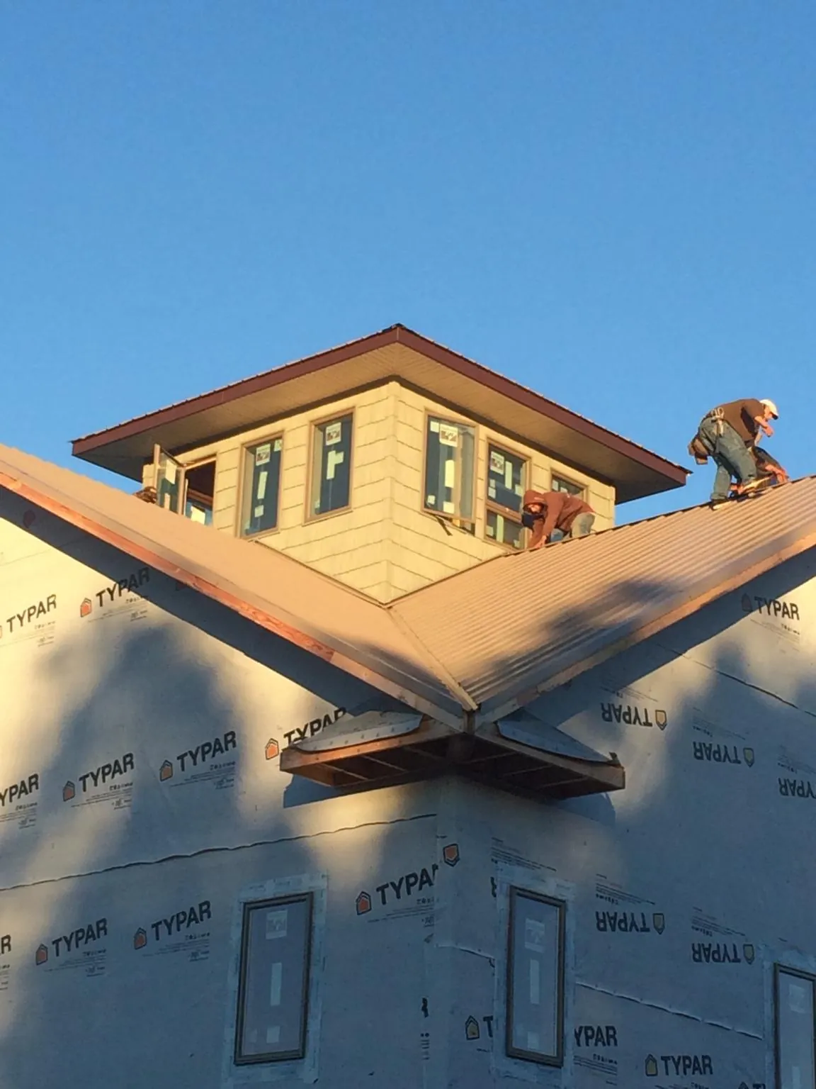 Roofers working around a rooftop cupola on a new metal roof at sunset — Roof Waterproofing in Maumee by Roofing Brothers
